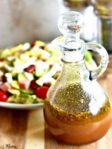Balsamic Vinaigrette Salad Dressing in a bottle with a salad and salt and pepper grinder in the background