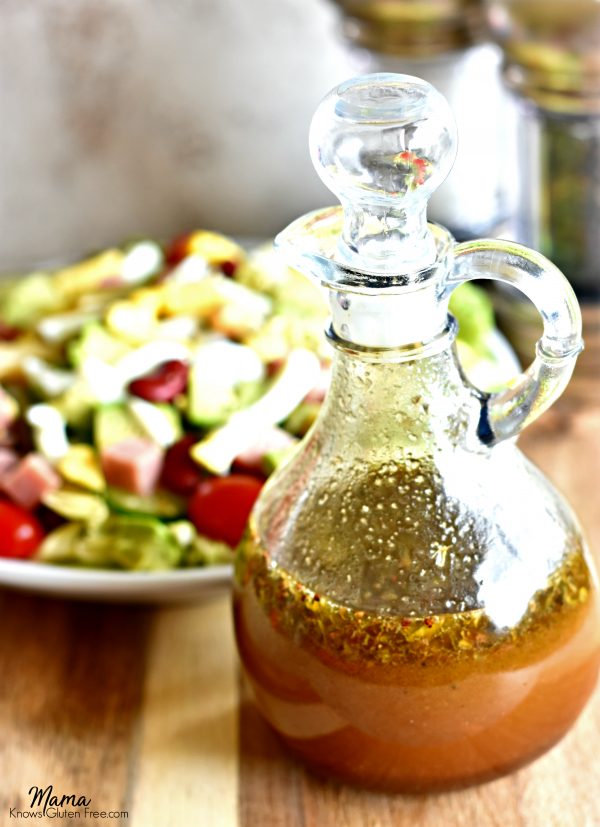 Balsamic Vinaigrette Salad Dressing in a bottle with a salad and salt and pepper grinder in the background