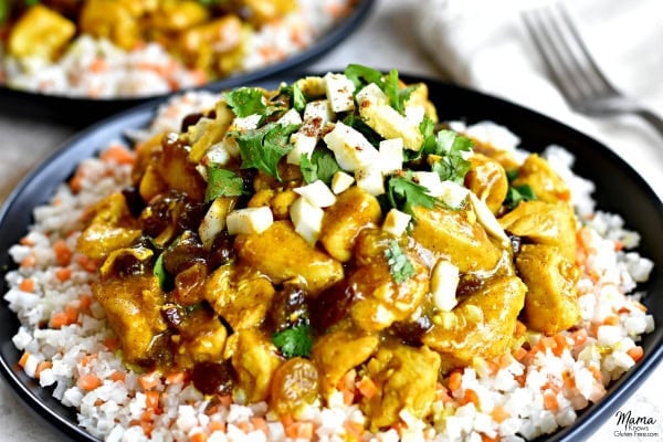 Gluten-Free Turmeric Coconut Chicken Curry served on cauliflower rice on a black plate with a fork and another plate in the background