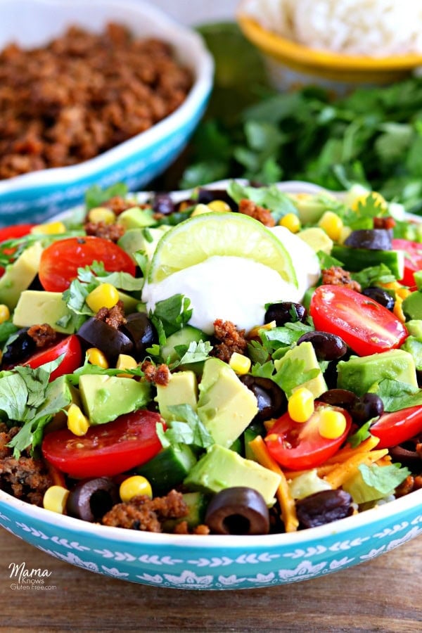 gluten-free burrito bowl with taco meat, rice and cilantro int he background