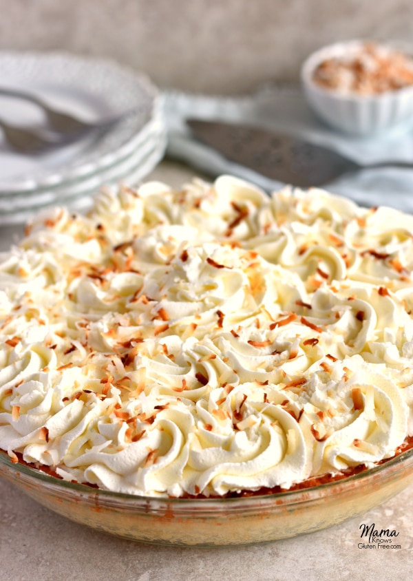A Gluten-Free Coconut Cream Pie with plates and shredded coconut in the background