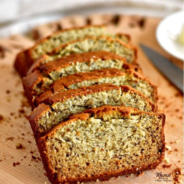 6 slices of gluten-free banana bread on a cutting board with a knife and butter