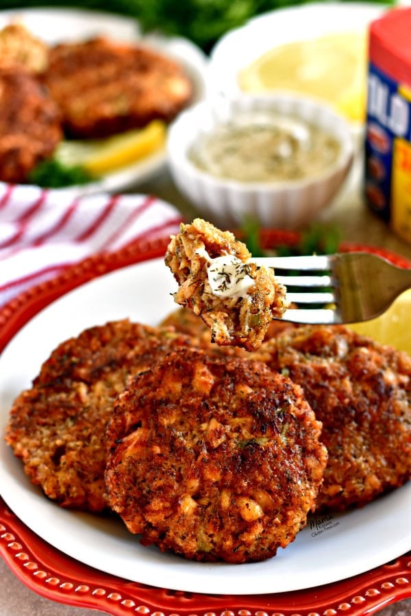 Fork with piece of Gluten-Free Salmon cake with a plate of 4 salmon cakes