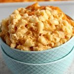 gluten-free macaroni and cheese in a blue bowl with a casserole dish in the background