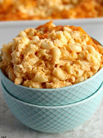 gluten-free macaroni and cheese in a blue bowl with a casserole dish in the background