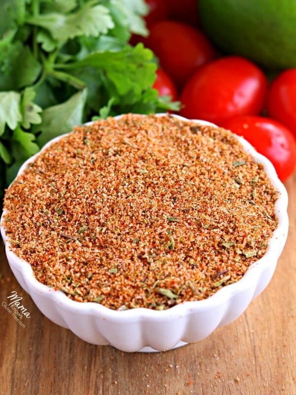 a bowl of gluten-free homemade taco seasoning with tomatoes, cilantro and avocado in the background