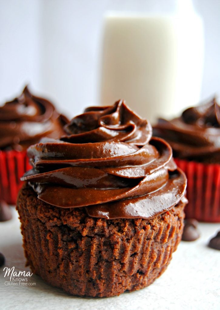 Three Paleo chocolate cupcakes with chocolate chips and a glass of milk