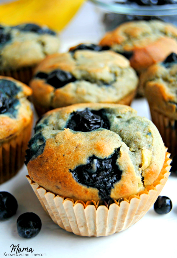 6 gluten-free blueberry banana muffins with bananas and blueberries in the background