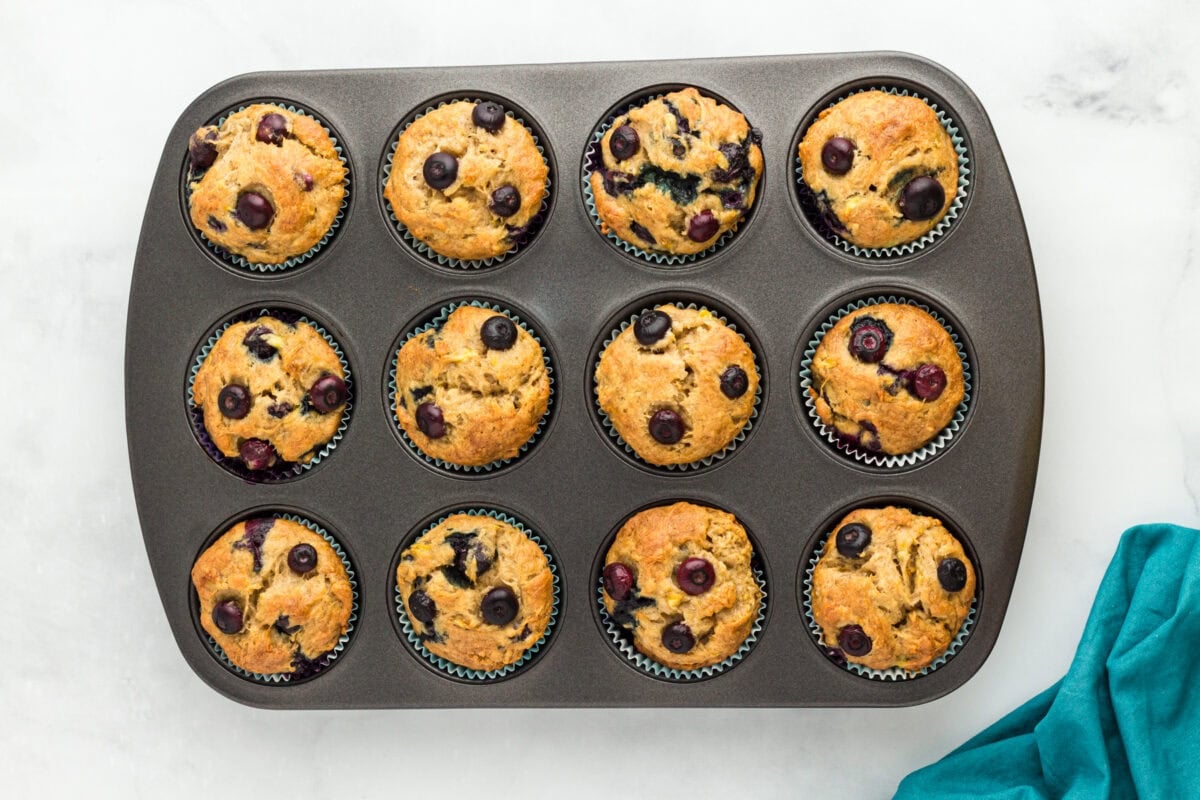 Freshly baked gluten-free blueberry banana muffins cooling in a muffin pan.