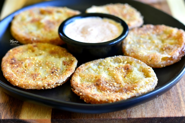 5 gluten-free fried green tomatoes on a black plate with remoulade sauce