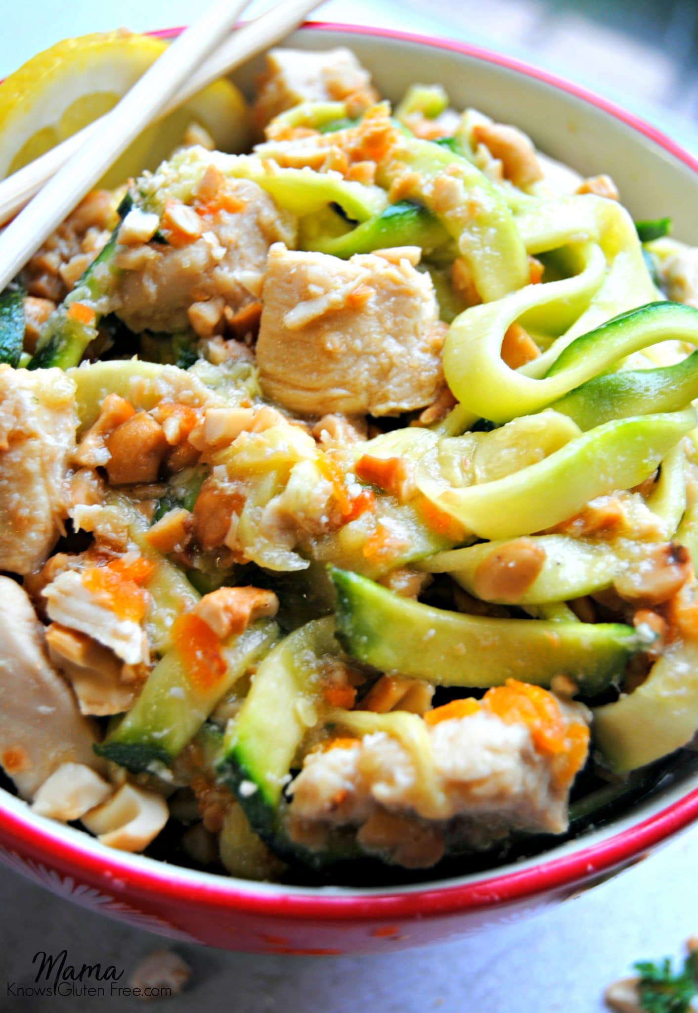honey lemon ginger chicken in a bowl with zucchini noodles with chopsticks and lemon slice 