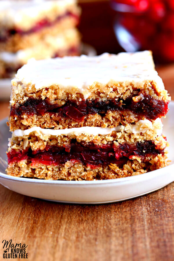gluten-free cranberry oatmeal bars on a white plate with cranberries in the background.