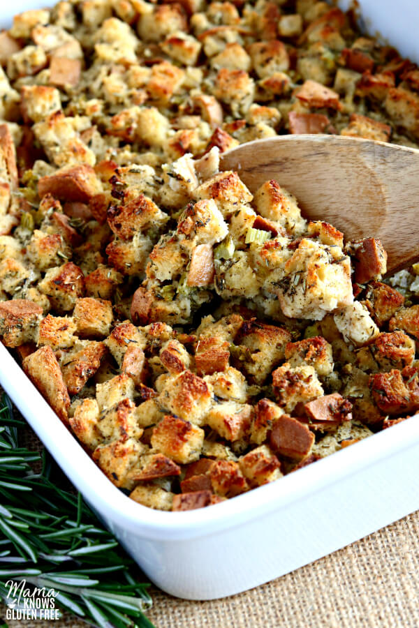 gluten-free stuffing in a white casserole dish with a wooden spoon