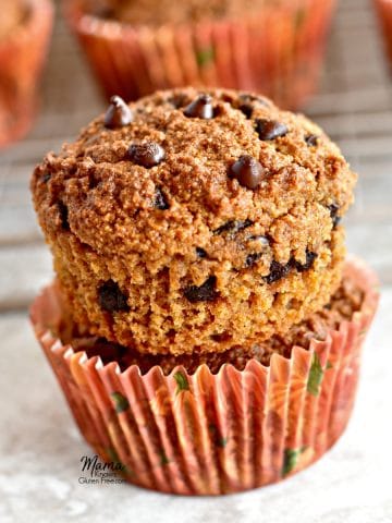 paleo pumpkin muffins stacked on top of each other with the muffins in the background