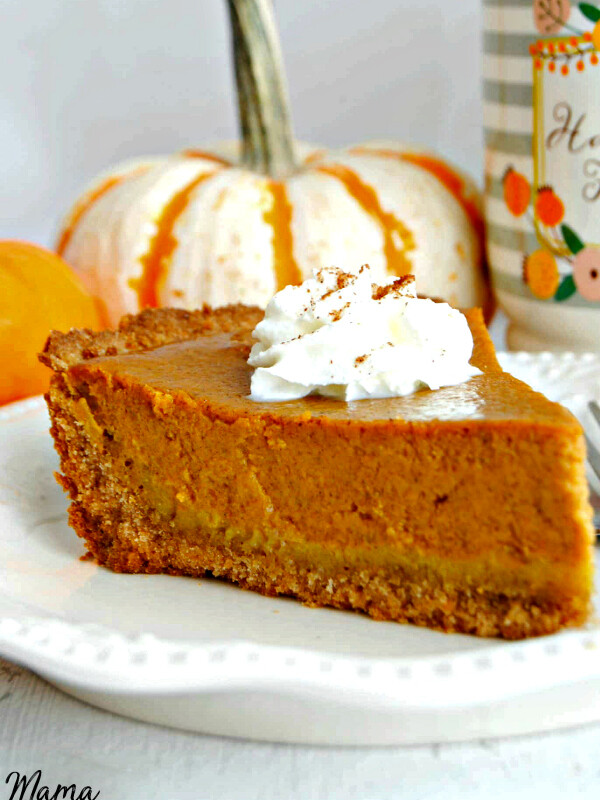 A slice of Easy Gluten-Free Pumpkin Pie with whipped cream of top with pumpkins and coffee cup in the background
