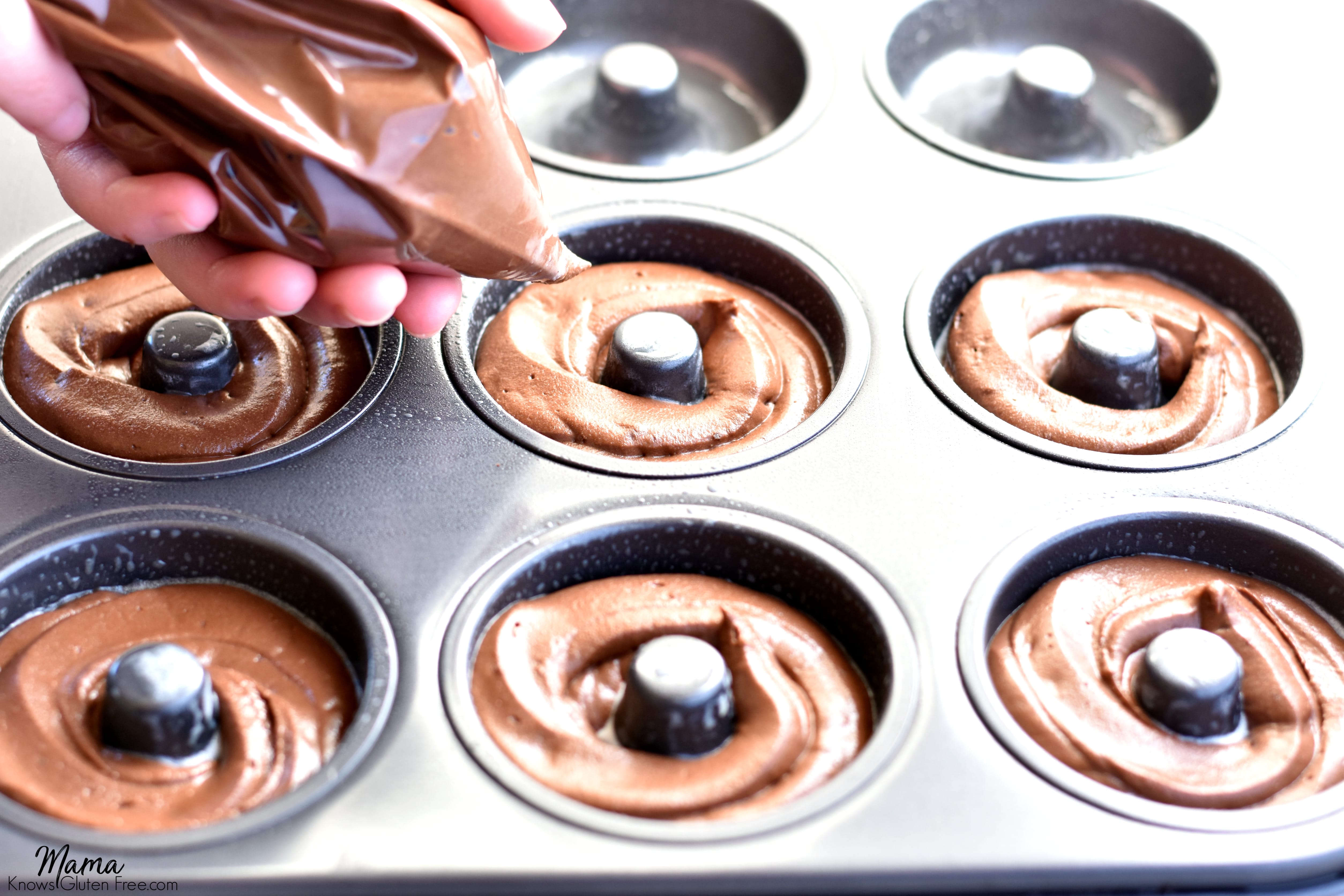 gluten-free chocolate donut batter being piped into a donut pan