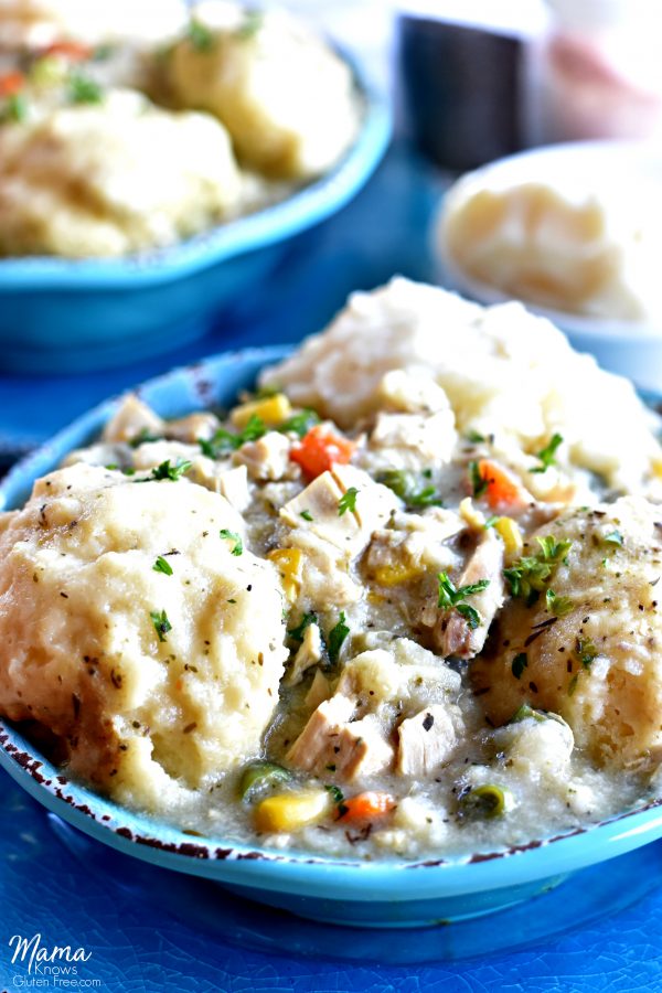 gluten-free chicken and dumplings in blue bowl with mashed potatoes and another bowl in the background
