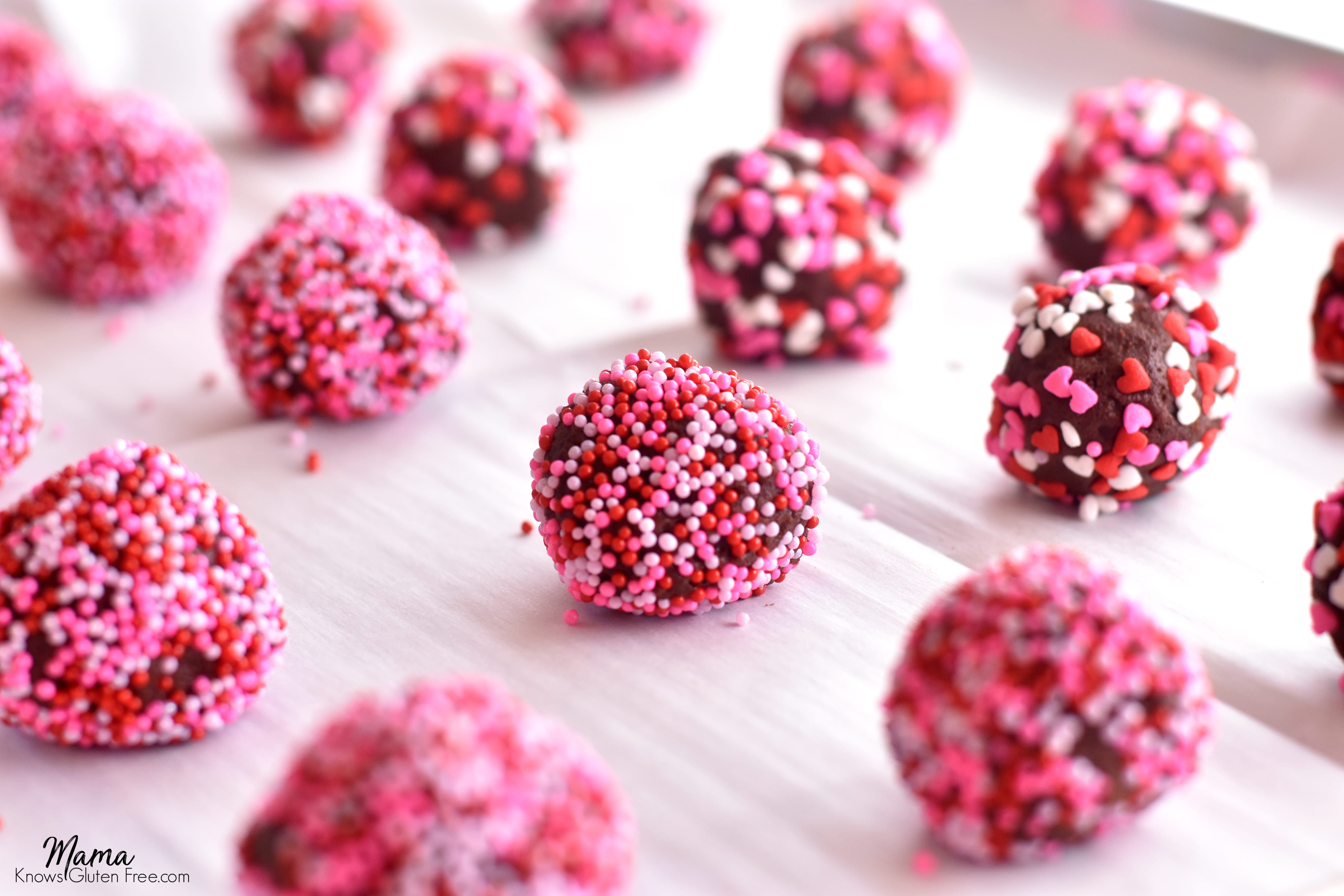 gluten-free chocolate kiss cookie balls covered in sprinkles on a cookie sheet