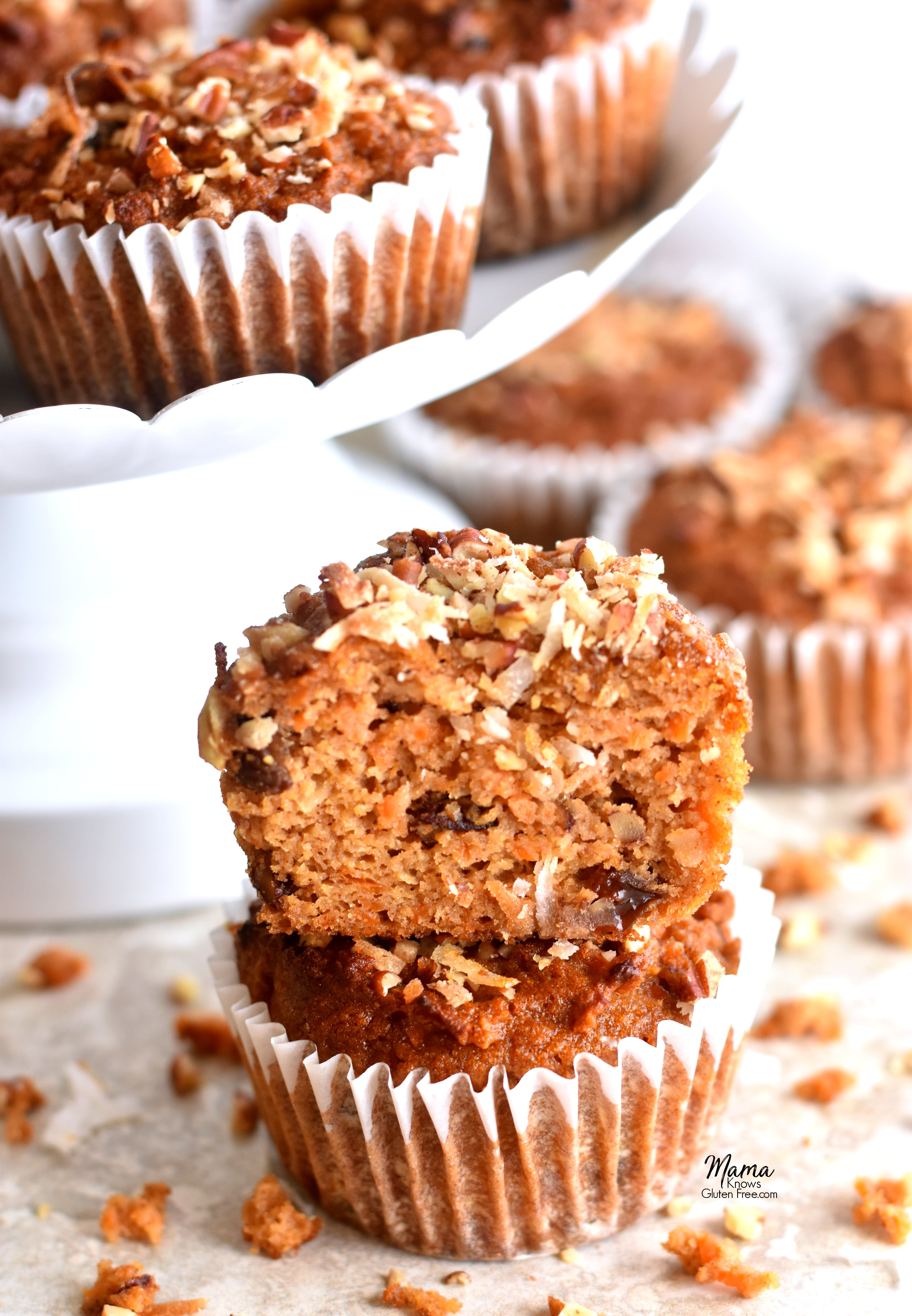a cut in half Paleo carrot cake muffins stacked on muffins with more muffins in the background