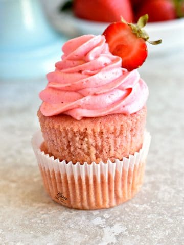 gluten-free strawberry cupcakes with strawberry buttercream and strawberries in the background