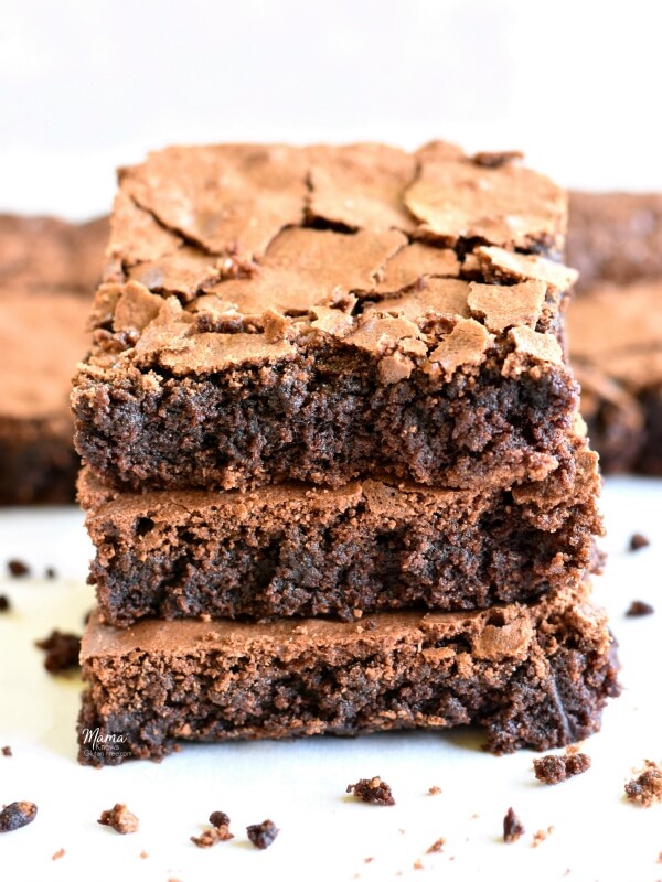 3 gluten-free brownies stacked on top of each other with brownies in the background