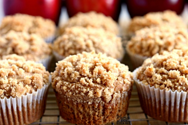 9 Easy Gluten-Free Apple Cinnamon Crumb Muffins on a cooling rack with apples in the background