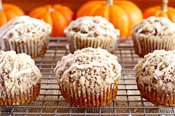 Six gluten-free pumpkin muffins on a cooking rack with pumpkins in the backgrounds