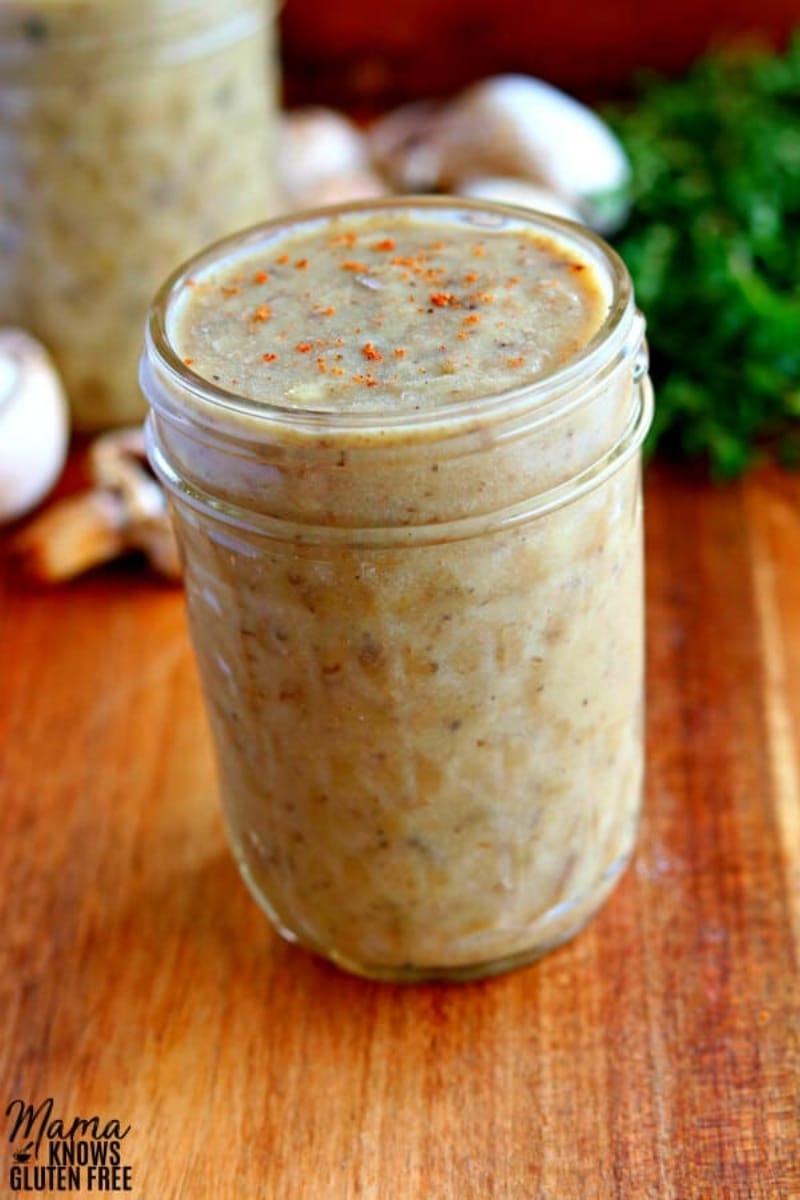 mason jar of gluten-free creamo of mushroom soup with mushrooms and thyme in the background