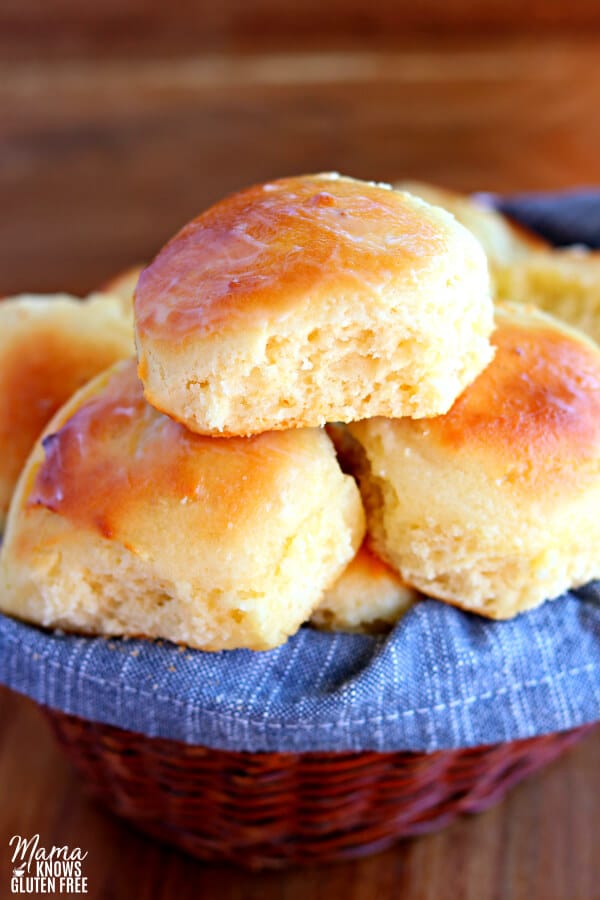 Gluten-free dinner rolls in a basket lined with a blue kitchen towel. 