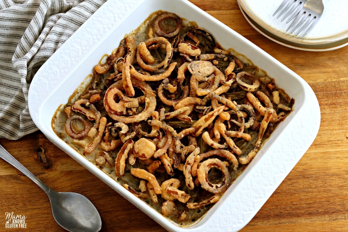 gluten-free green bean casserole in a white baking dish with a spoon and plates
