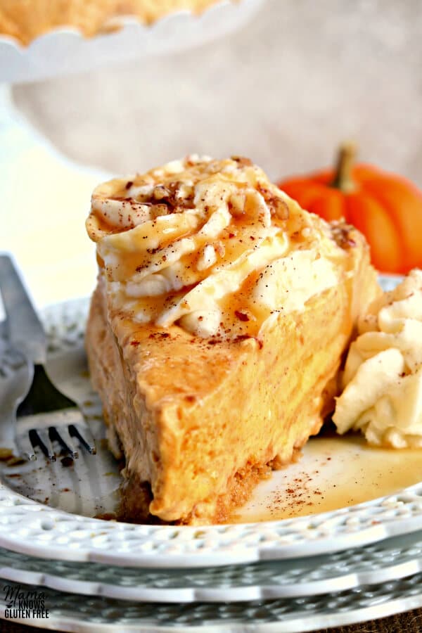 gluten-free pumpkin cheesecake on a white plate with a fork and a pumpkin in the background