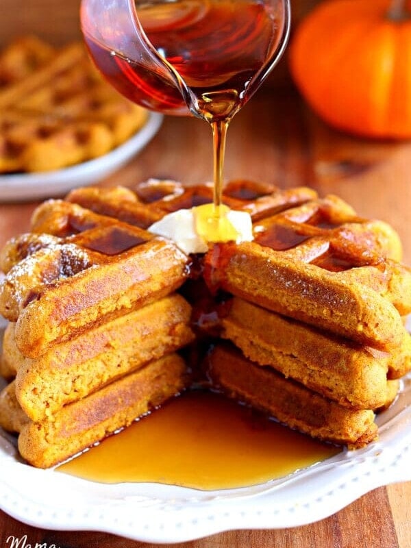 three gluten-free pumpkin waffels ona plate with syrup being poured on it