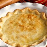 gluten-free baked pie crust with apples and a rolling pin in the background