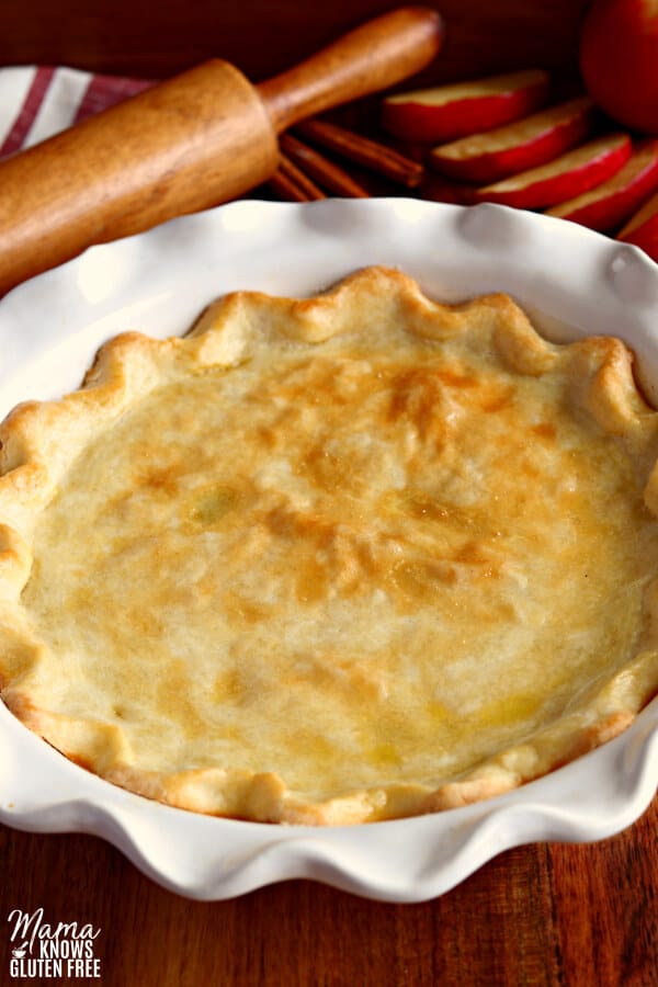 gluten-free baked pie crust with apples and a rolling pin in the background
