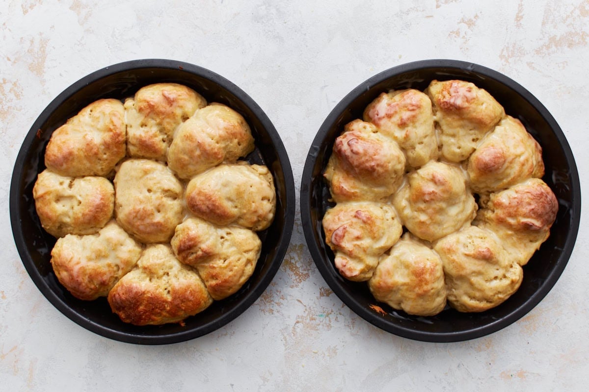 Gluten-free dinner rolls in two cake pans, brushed with melted butter.
