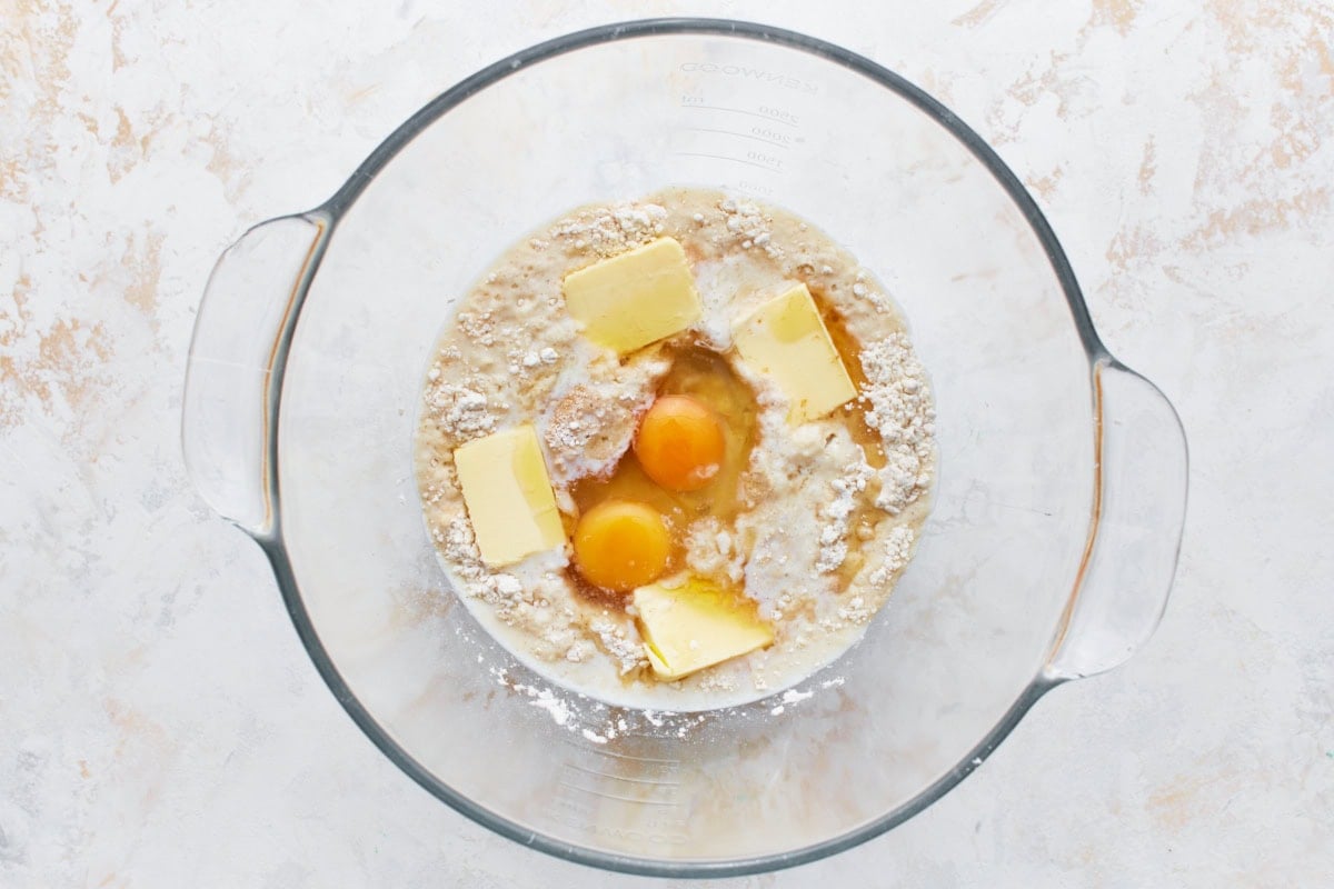 Eggs and butter added to gluten-free flour mixture in a glass bowl.