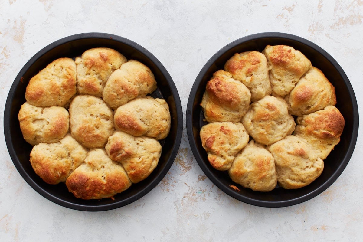 Freshly baked gluten-free dinner rolls in two cake pans.
