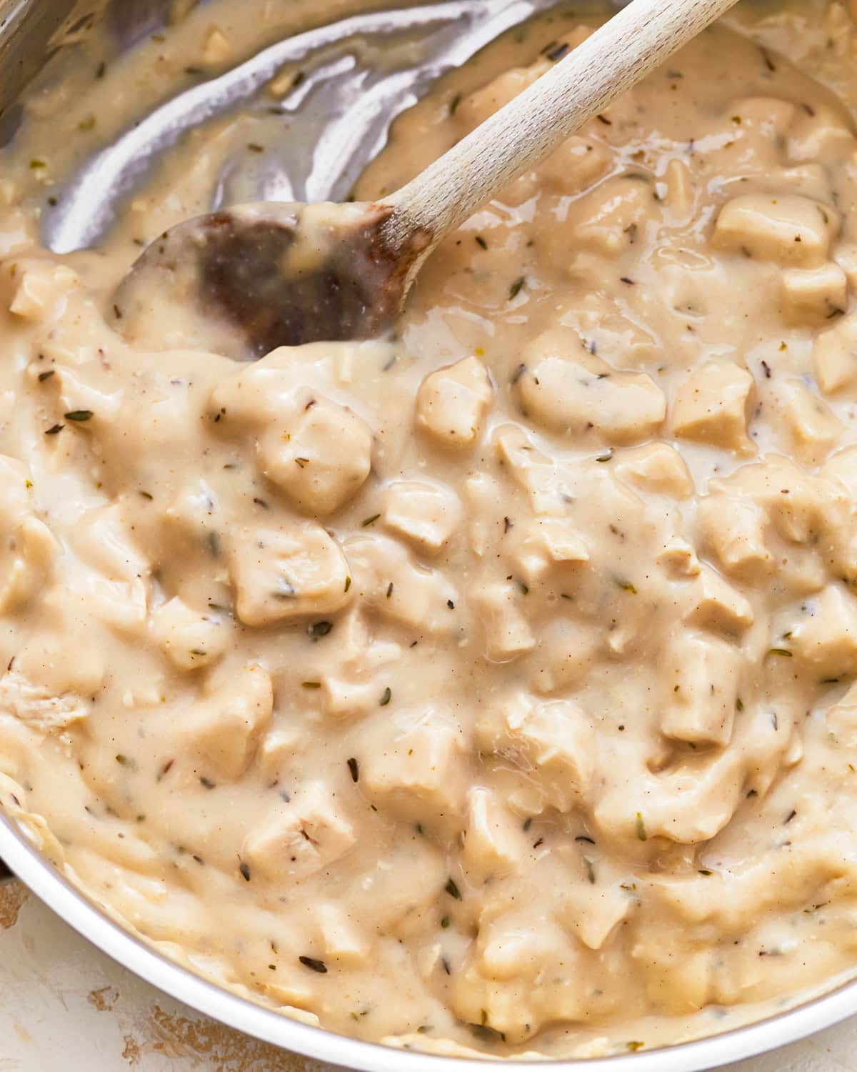 A wooden spoon stirring gluten-free cream of chicken soup in a pan