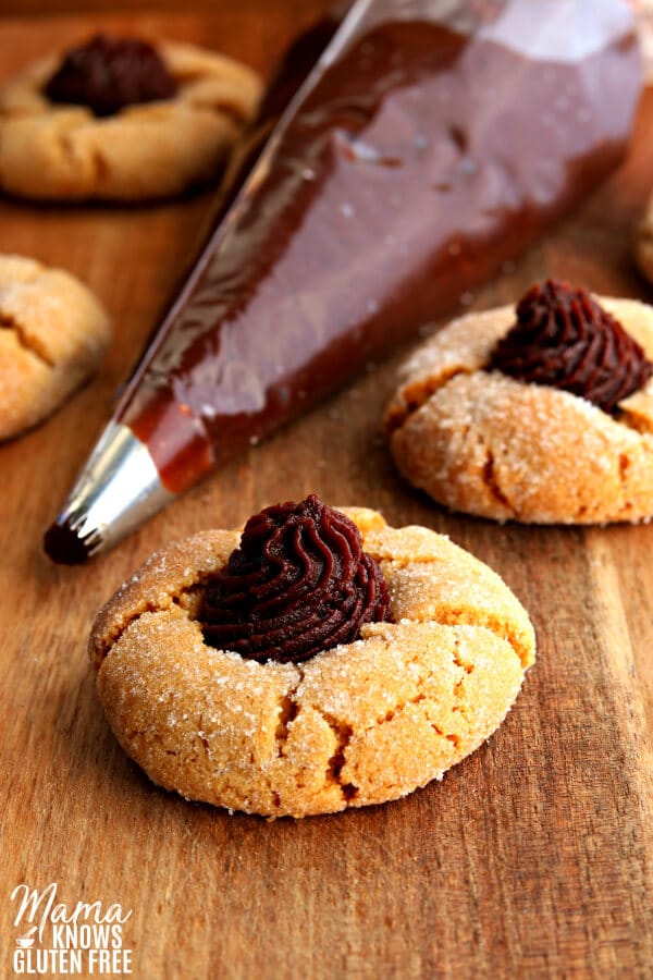 gluten-free and dairy-free peanut butter blossom cookies with chocolate peanut butter filling in a piping bag