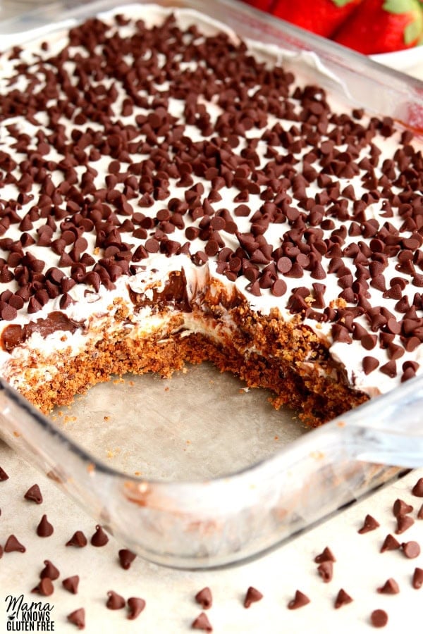 a pan of chocolate lasagna dessert with one slice cut out and strawberries in the background