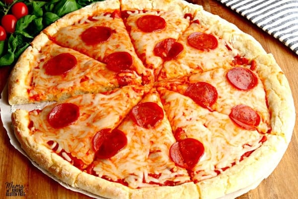 gluten-free cheese and pepperoni pizza with tomatoes, basil and a kitchen towel in the background