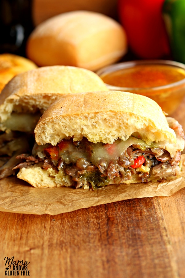 an instant pot steak sandwich but in half with a roll and au jus in the backgorund