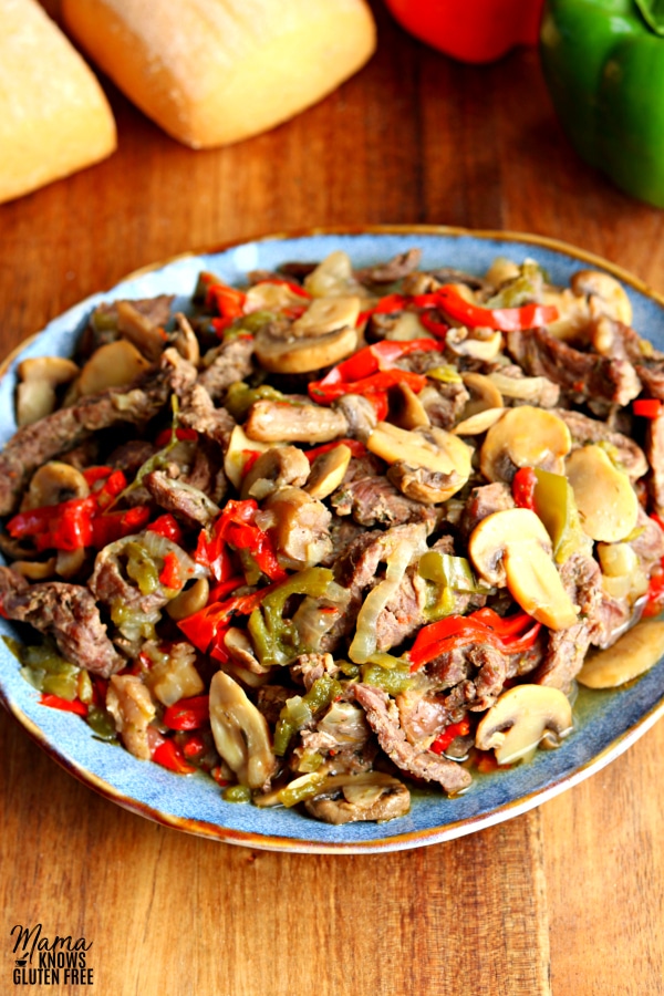 a blue plate full of cooked sliced steak, bell peppers, mushrooms, and ions. 