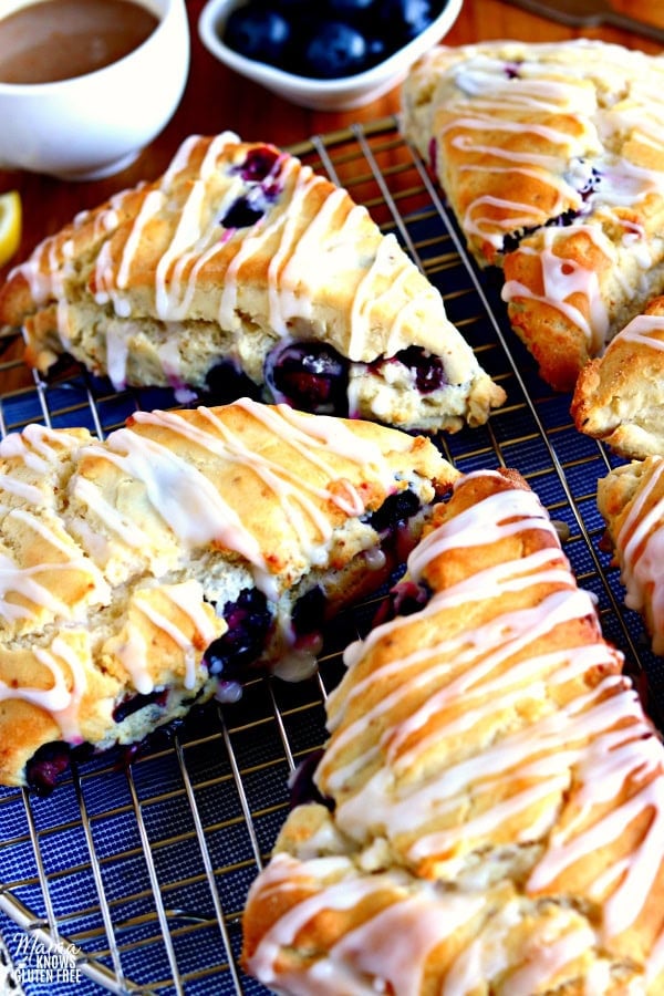 cooling rack with 6 gluten-free blueberry scones with a cup of coffee, lemon and blueberries in the background