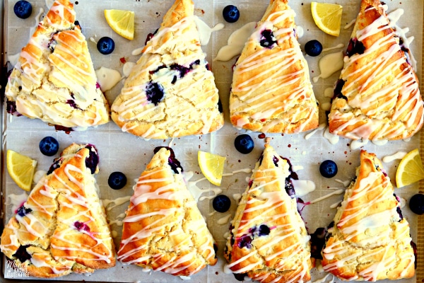 gluten-free blueberry scones on a baking pan with blueberries and lemon pieces