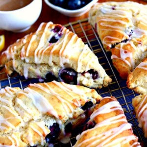 cooing rack with gluten-free blueberry scones with blueberries and a cup of coffee on the background