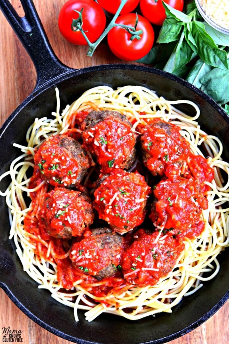 gluten-free meatballs on top of spaghetti and tomato sauce in cast iron pan