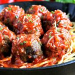 gluten-free meatballs on top of spaghetti covered in tomato sauce, parsley, and Parmesan cheese