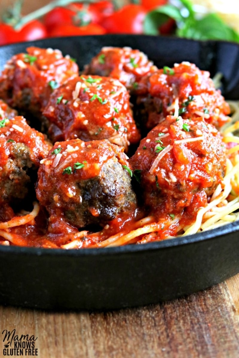 gluten-free meatballs over spaghetti in cast iron pan