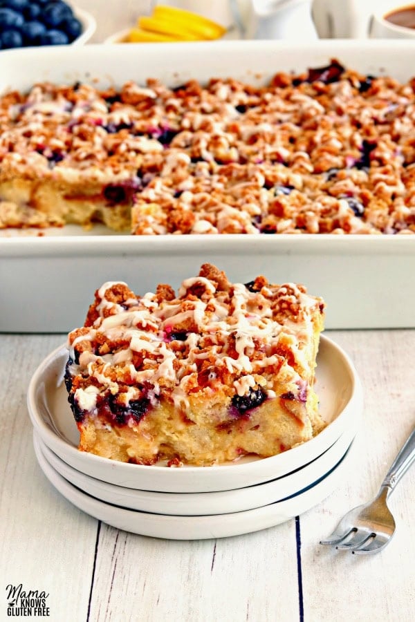 a slice of gluten-free blueberry breakfast casserole on a plate with the casserole in the background